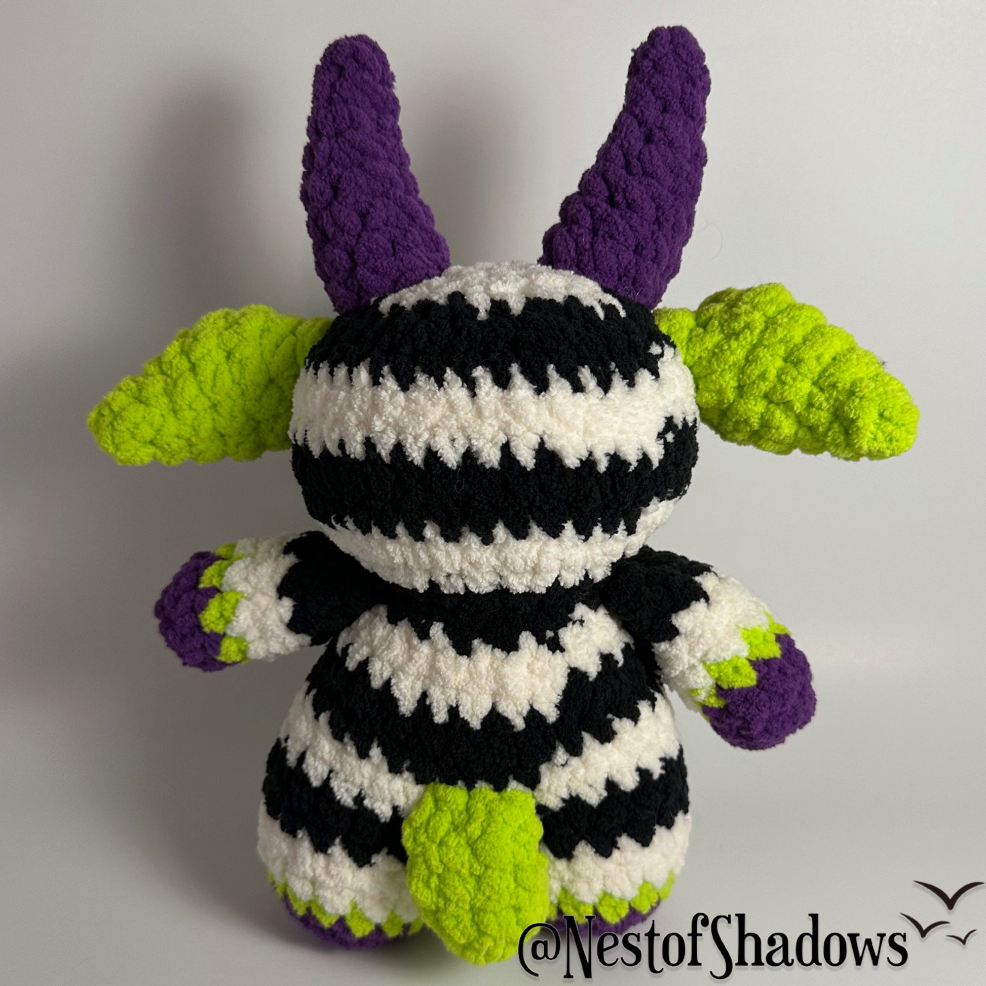 Crochet goat with stripes and white background. Nest of Shadows watermark.