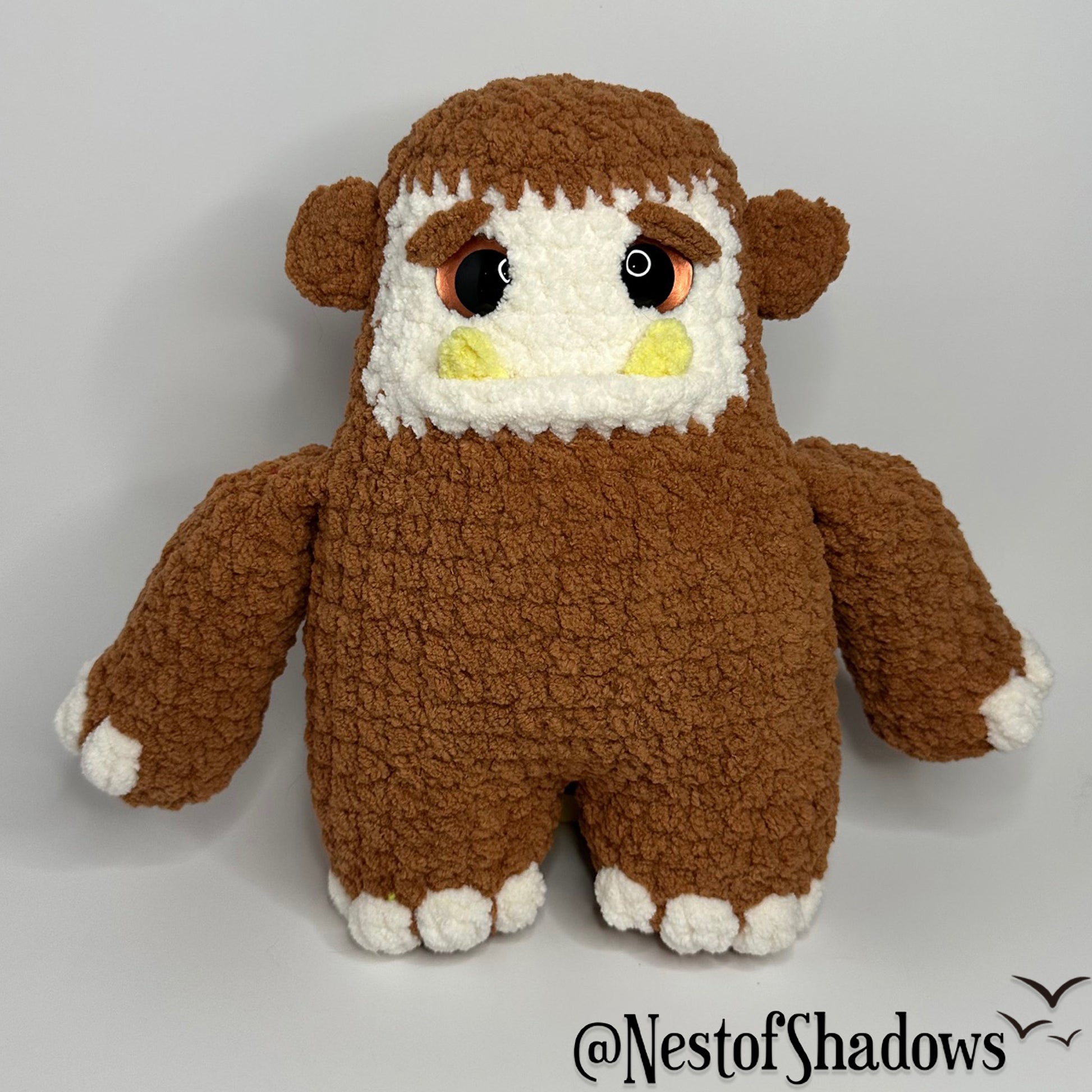 Bigfoot crochet plushie with a while background and Nest of Shadows watermark.