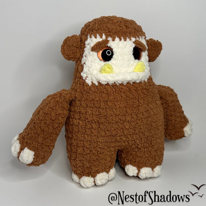 Bigfoot crochet plushie with a while background and Nest of Shadows watermark.