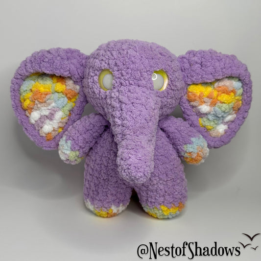 Purple crochet elephant with a white background and Nest of Shadows watermark