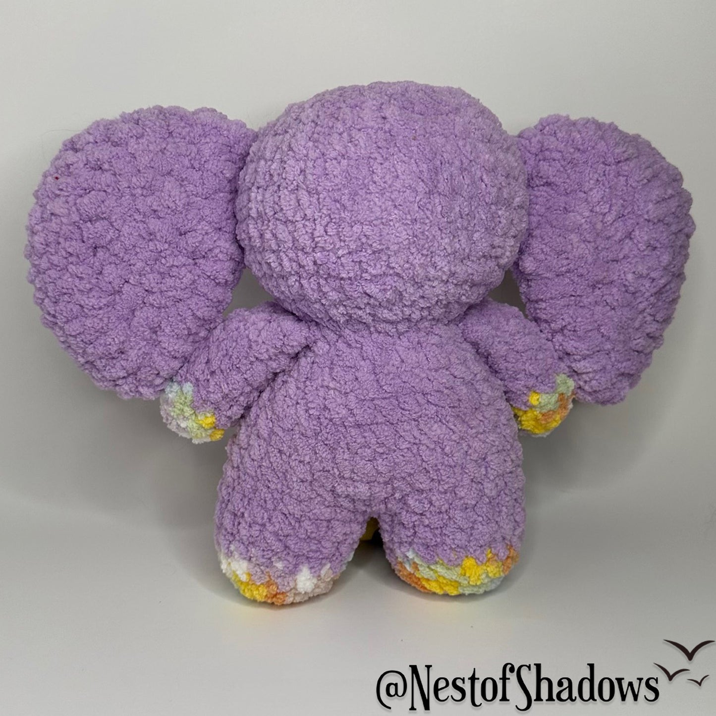 Purple crochet elephant with a white background and Nest of Shadows watermark