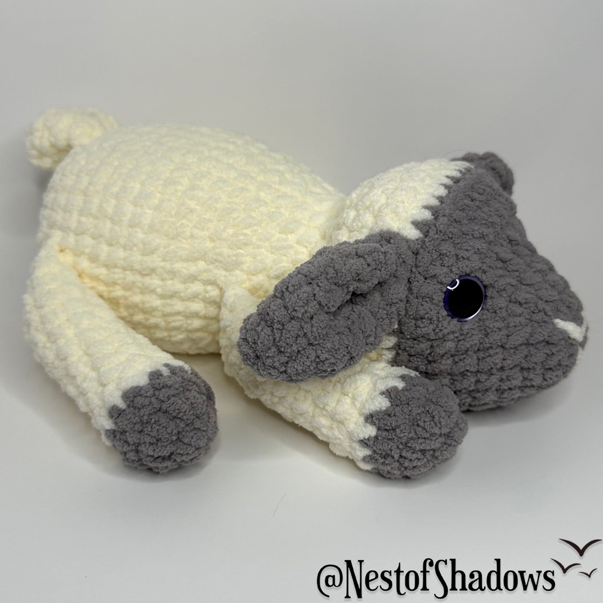 Gray and white crochet lab plushie with a white background and Nest of Shadows watermark.